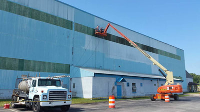 large factory building being painted using scaffold lift 