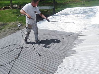 man painting large metal roof