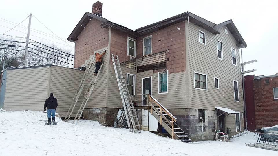 workers installing siding on a house during winter