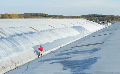 man painting large metal roof