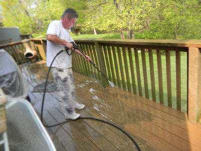 man pressure-washing power-washing wooden deck